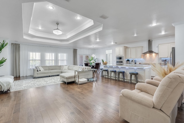 living room with ornamental molding, hardwood / wood-style floors, and a tray ceiling