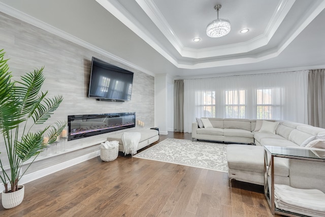 living room with hardwood / wood-style floors, crown molding, a chandelier, and a raised ceiling