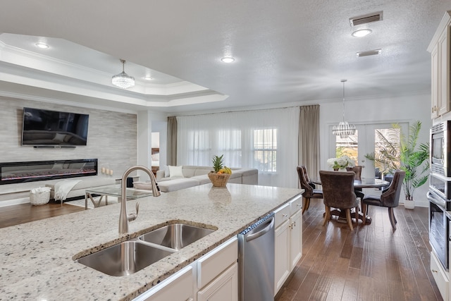 kitchen featuring appliances with stainless steel finishes, white cabinets, decorative light fixtures, sink, and light stone counters