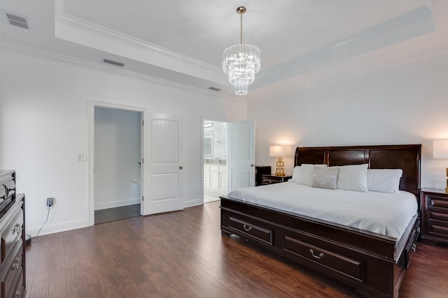 bedroom featuring connected bathroom, an inviting chandelier, dark hardwood / wood-style floors, a raised ceiling, and crown molding