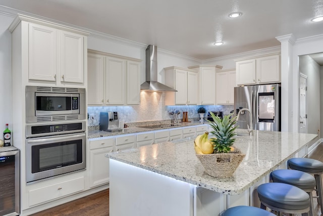 kitchen featuring backsplash, appliances with stainless steel finishes, wall chimney range hood, and a center island with sink