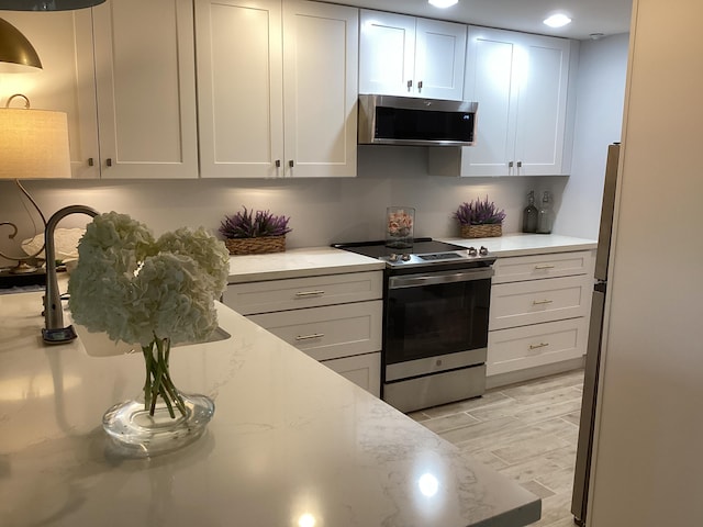 kitchen with light stone countertops, stainless steel appliances, and white cabinets