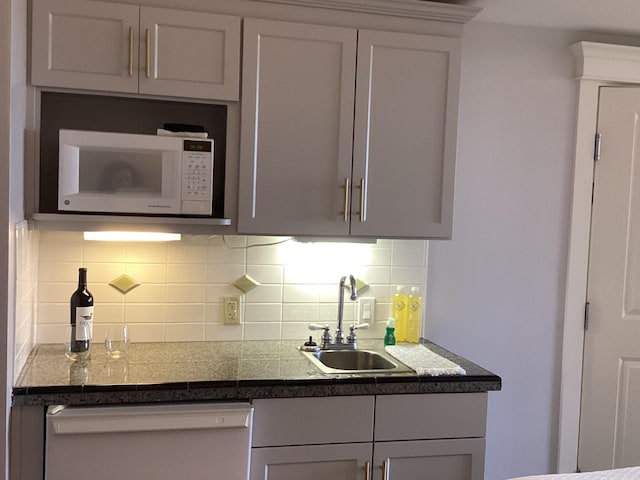 kitchen featuring sink, dishwashing machine, and backsplash