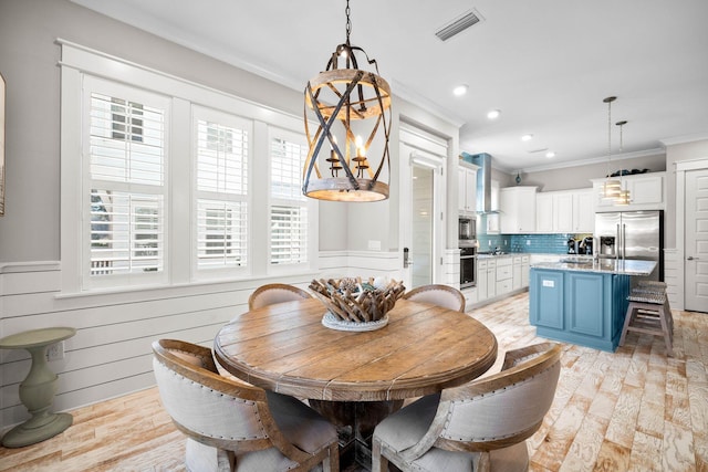 dining area with ornamental molding and light hardwood / wood-style floors