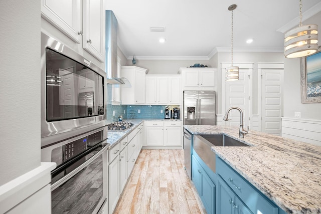 kitchen featuring blue cabinets, white cabinets, appliances with stainless steel finishes, and crown molding