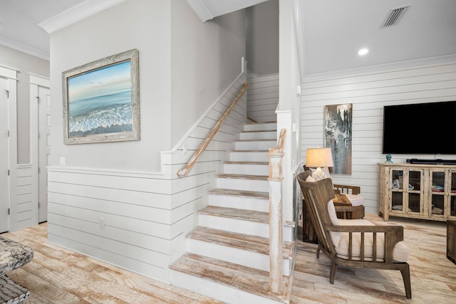 stairs with ornamental molding and hardwood / wood-style flooring