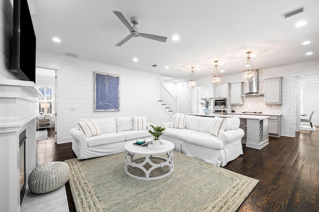 living room with dark wood-type flooring and ceiling fan