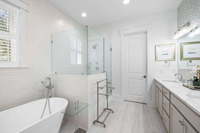 bathroom featuring vanity, independent shower and bath, and tile walls