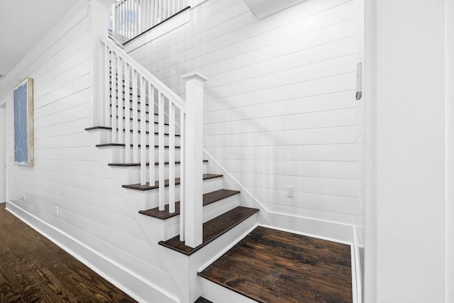 stairway featuring hardwood / wood-style flooring and wood walls