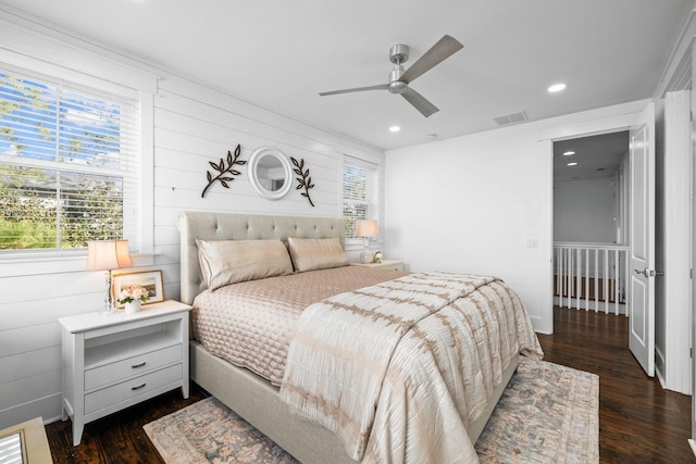 bedroom featuring ceiling fan, dark hardwood / wood-style floors, and multiple windows