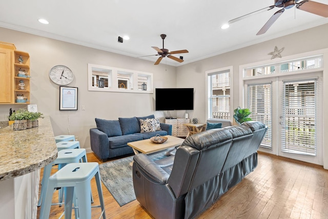 living room with light hardwood / wood-style flooring, crown molding, and plenty of natural light