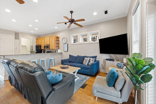 living room with ornamental molding, light wood-type flooring, and ceiling fan