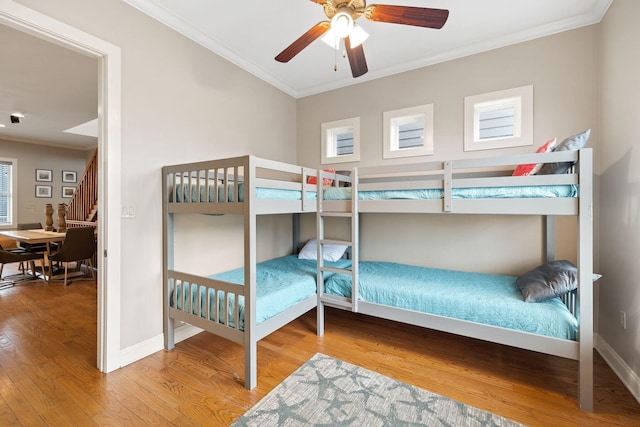 bedroom with ceiling fan, crown molding, and wood-type flooring