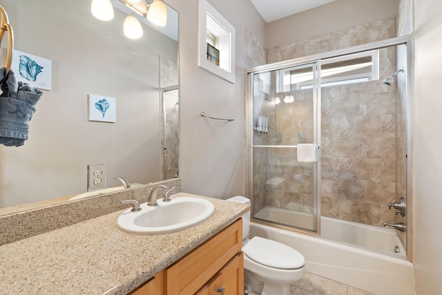 full bathroom featuring tile patterned flooring, bath / shower combo with glass door, vanity, and toilet