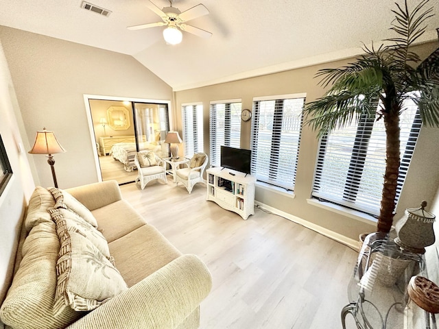 living room with ceiling fan, lofted ceiling, and light hardwood / wood-style flooring