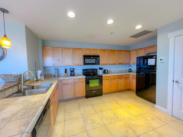 kitchen featuring sink, tile counters, black appliances, and pendant lighting