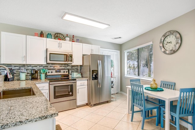 kitchen with sink, light stone counters, white cabinetry, and stainless steel appliances