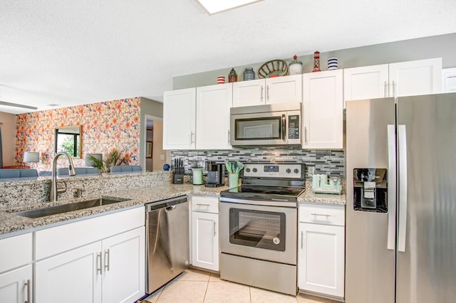 kitchen with light tile patterned floors, sink, white cabinets, and stainless steel appliances