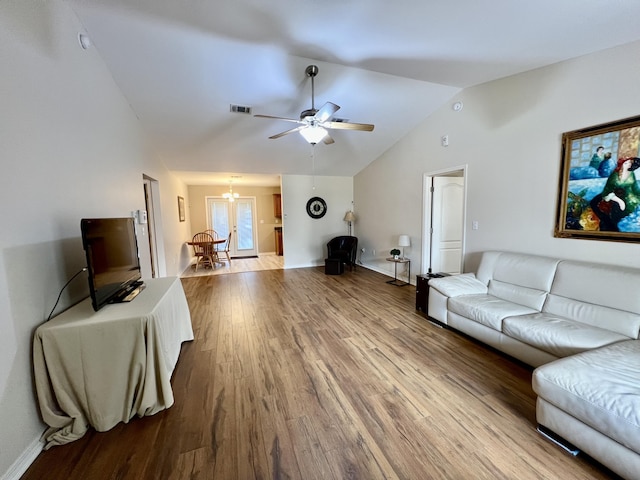 living room with lofted ceiling, wood-type flooring, and ceiling fan with notable chandelier