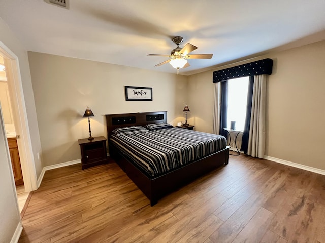 bedroom with ceiling fan, wood-type flooring, and connected bathroom