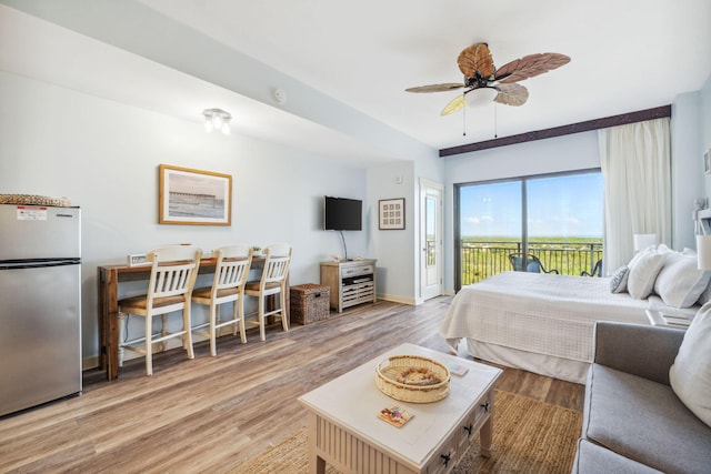 bedroom with stainless steel refrigerator, light wood-type flooring, ceiling fan, and access to exterior