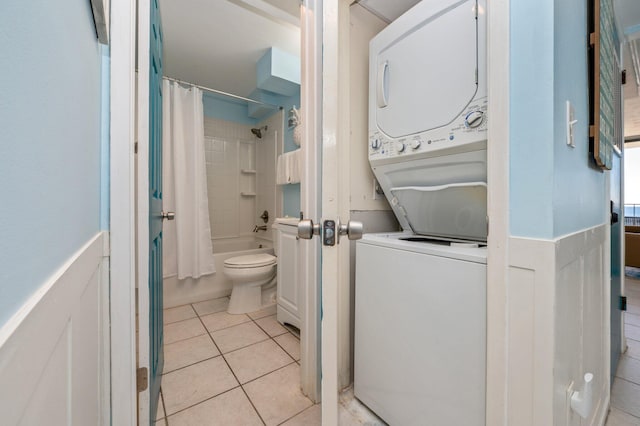 clothes washing area featuring light tile patterned floors and stacked washer and dryer