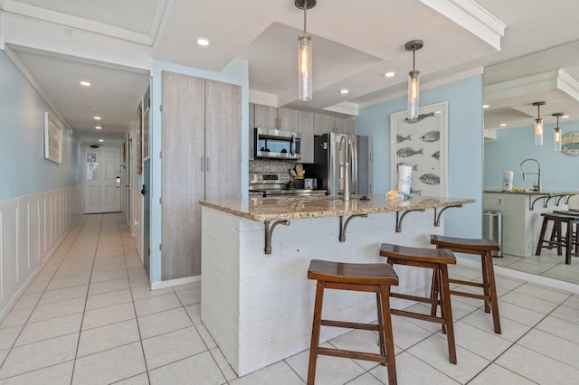 kitchen featuring kitchen peninsula, stainless steel appliances, backsplash, pendant lighting, and light stone counters