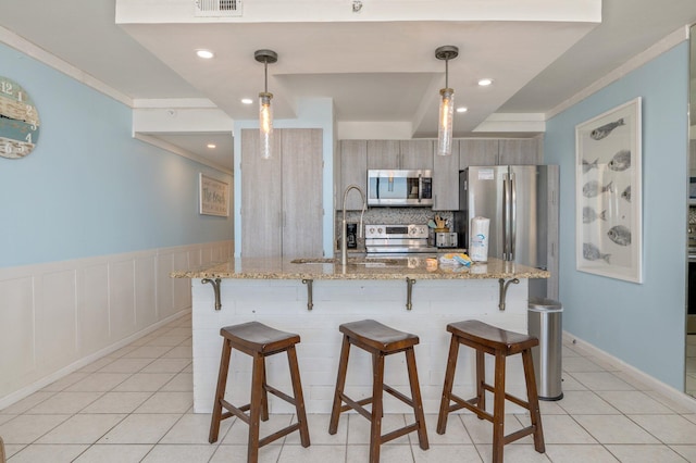 kitchen featuring stainless steel appliances, a kitchen bar, hanging light fixtures, and sink