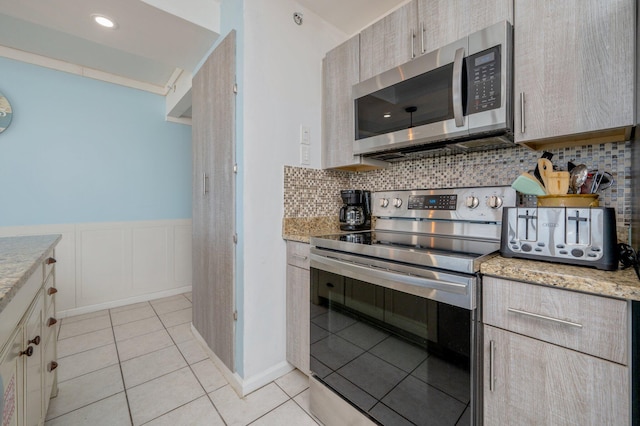 kitchen with light stone countertops, light tile patterned floors, appliances with stainless steel finishes, and tasteful backsplash