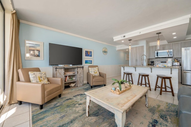 living room with light tile patterned flooring, crown molding, and sink