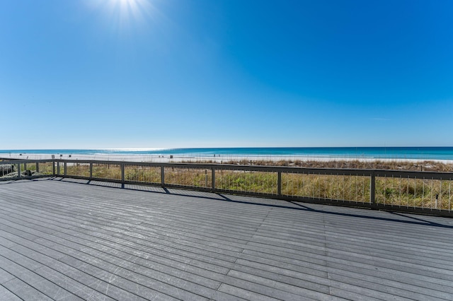 wooden terrace featuring a water view and a beach view