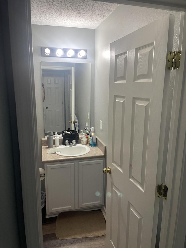 bathroom with a textured ceiling, hardwood / wood-style flooring, and vanity