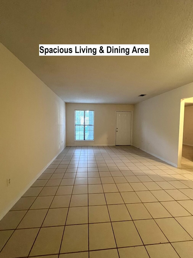 unfurnished room with a textured ceiling and light tile patterned floors