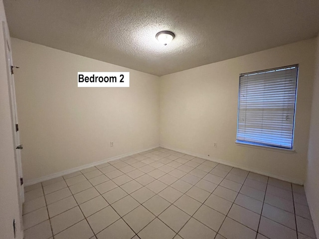 tiled spare room featuring a textured ceiling