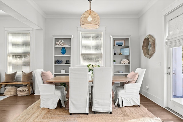 dining room with dark wood-type flooring, ornamental molding, and plenty of natural light