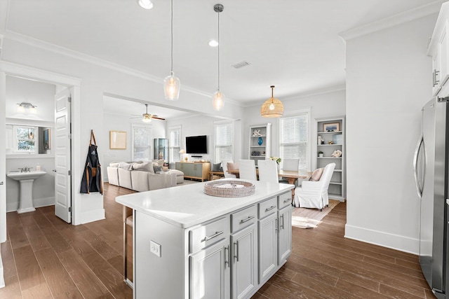 kitchen with decorative light fixtures, ceiling fan, a kitchen island, stainless steel refrigerator, and dark wood-type flooring