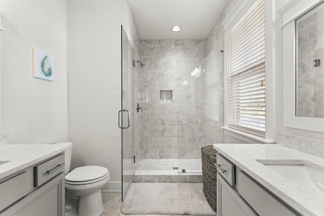 bathroom with toilet, a shower with door, and vanity