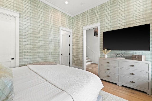 bedroom featuring ensuite bath, light wood-type flooring, and crown molding