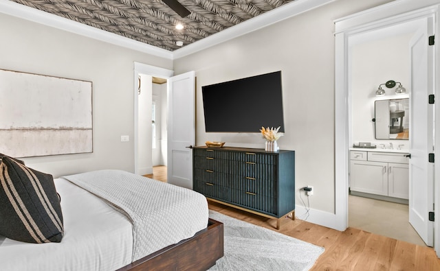 bedroom featuring sink, ensuite bathroom, light hardwood / wood-style floors, and crown molding