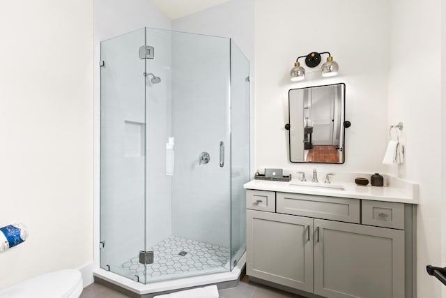 bathroom with toilet, tile patterned floors, a shower with shower door, and vanity