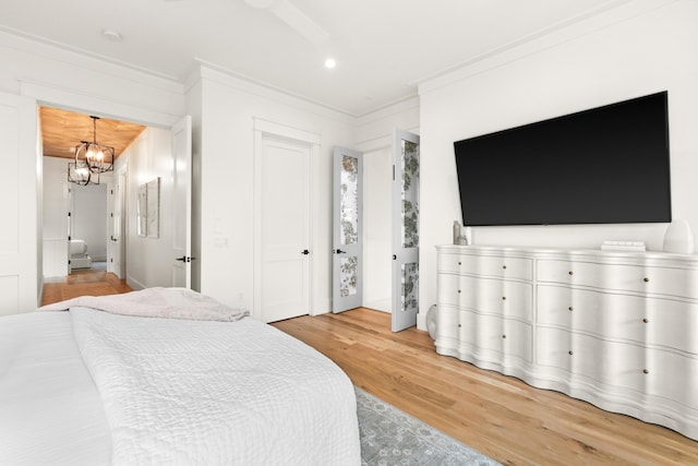 bedroom with ornamental molding, ceiling fan with notable chandelier, and wood-type flooring