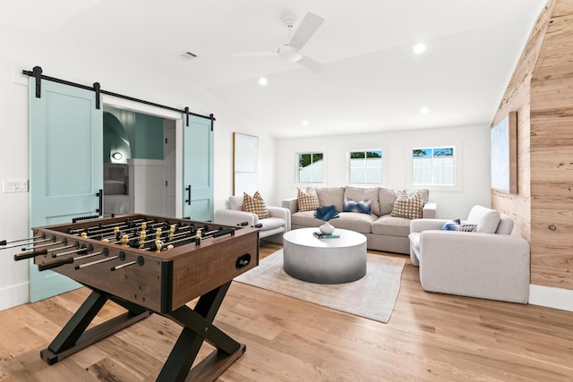 recreation room featuring light hardwood / wood-style floors, ceiling fan, a barn door, and lofted ceiling