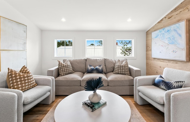 living room featuring lofted ceiling, wooden walls, and hardwood / wood-style floors