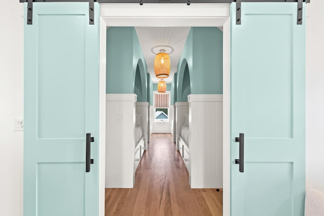 hallway with light wood-type flooring and a barn door