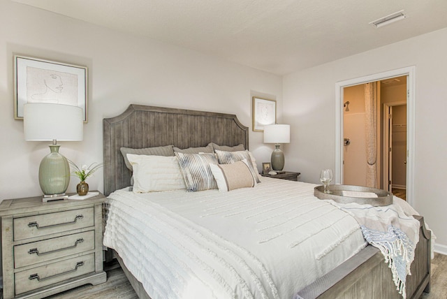 bedroom with ensuite bath and light hardwood / wood-style flooring