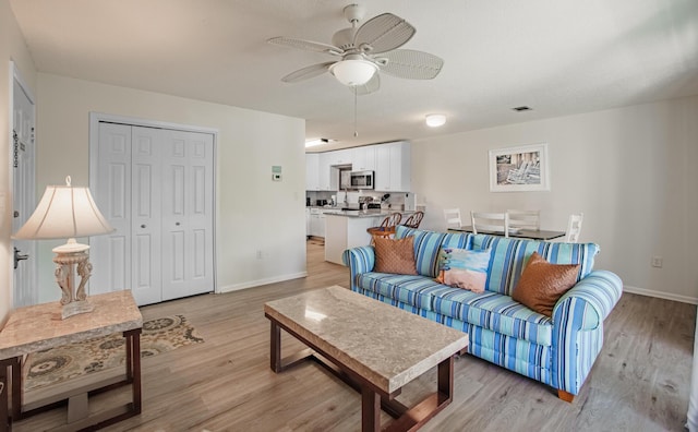 living room featuring ceiling fan and light hardwood / wood-style floors