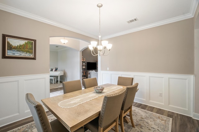 dining area with dark hardwood / wood-style flooring, crown molding, and an inviting chandelier