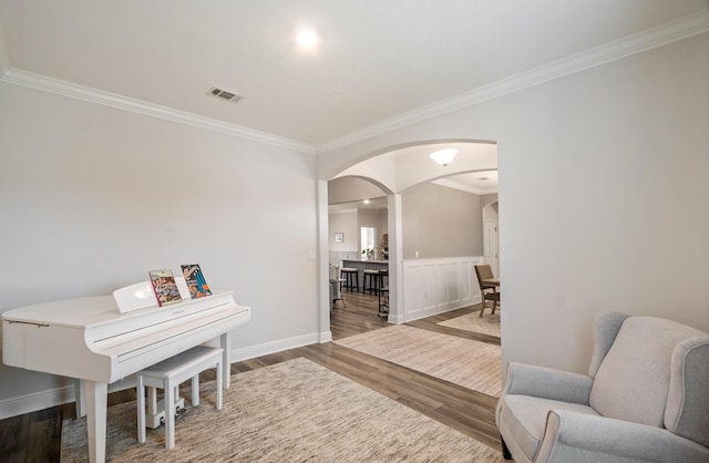 living area with ornamental molding and hardwood / wood-style flooring