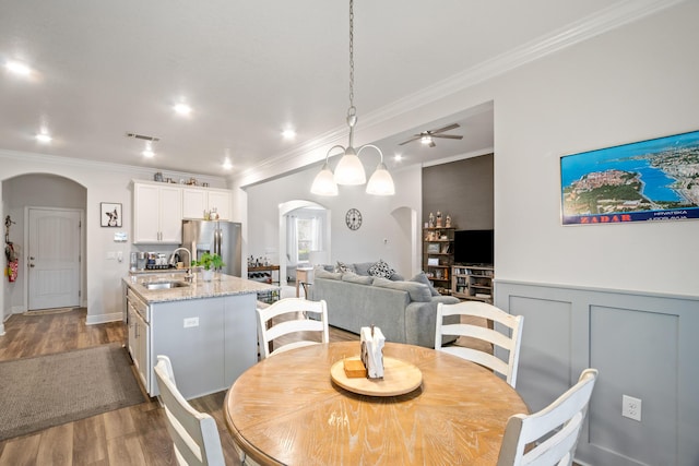 dining area with ceiling fan, sink, crown molding, and hardwood / wood-style floors