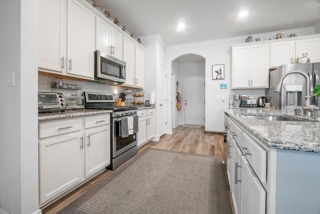 kitchen featuring light stone counters, hardwood / wood-style floors, white cabinets, and stainless steel appliances